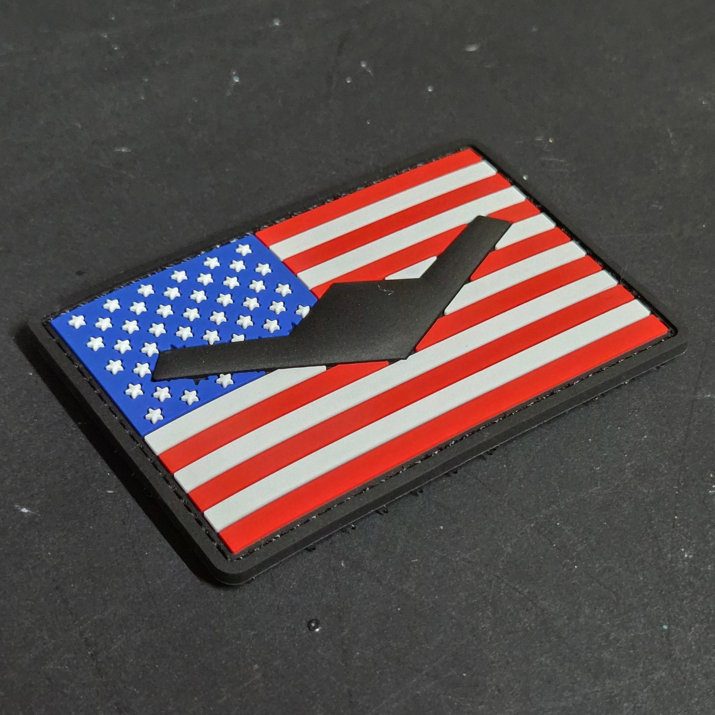 American flag patch with a black silhouette B-21 on a dark surface